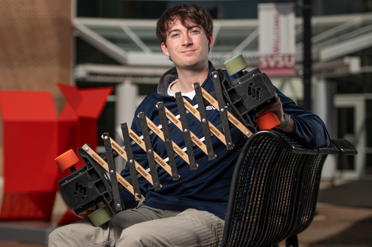 Young man sitting on bench holding longboard